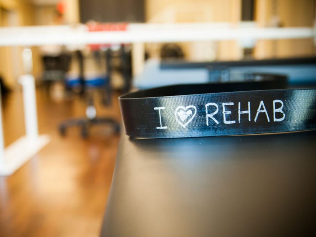 A black wristband that say I love Rehab sits on a table in a post acute office