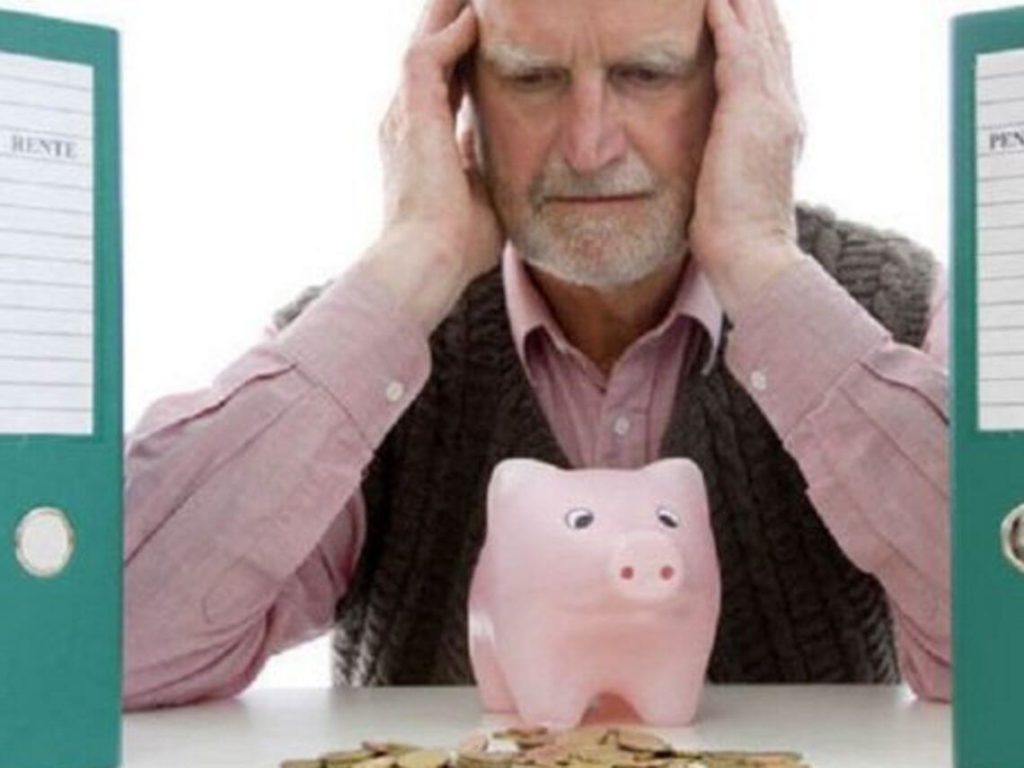 An older man is worryingly looking at a piggy bank while dealing with money problems