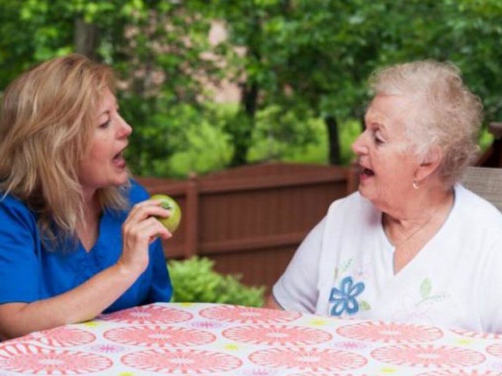 A nurse is helping an older woman dealing with speech loss