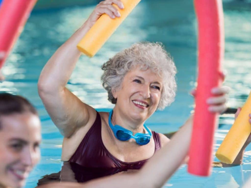 A senior woman is in the pool with pool noodles long term