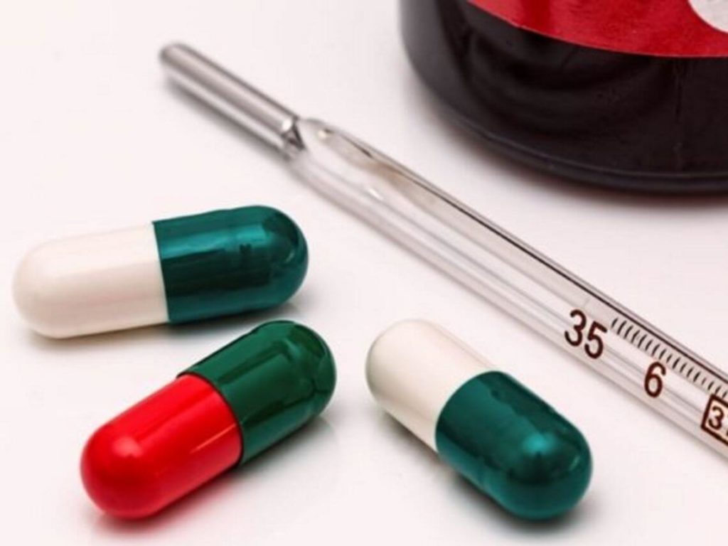 Pills next to a syringe that will help with the flu