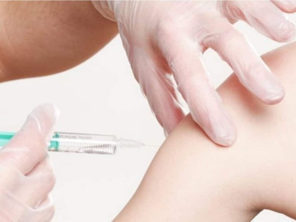 naked arm getting a vaccine shot by physician with gloved hands to fight the flu