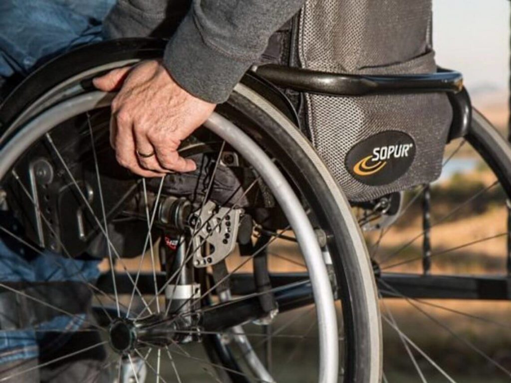 Aging senior in a wheel chair holding on to the spokes of his chair. Rehabilitation Therapy