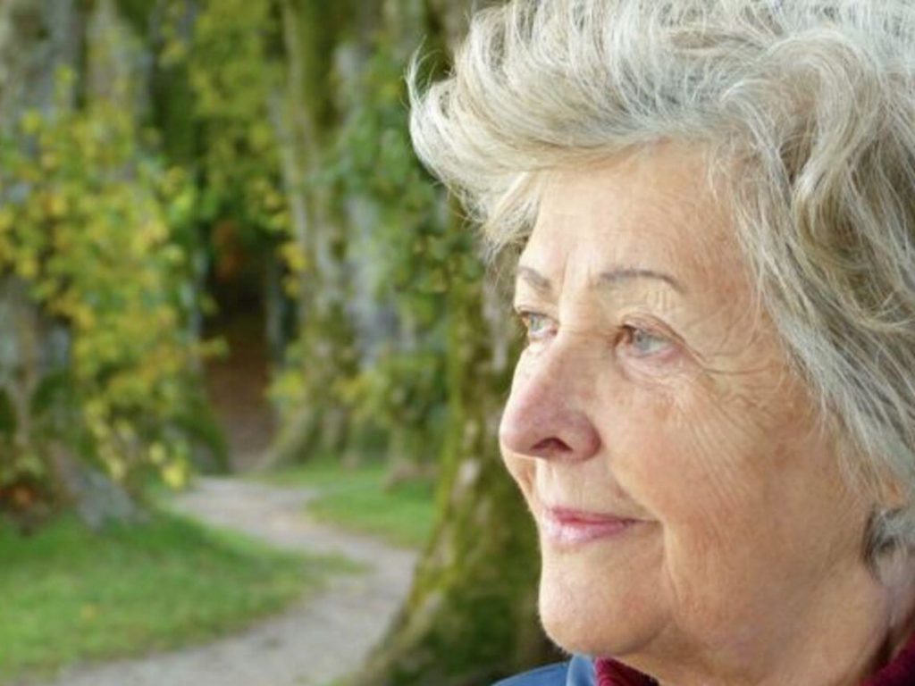 A senior woman looks out at into a city park