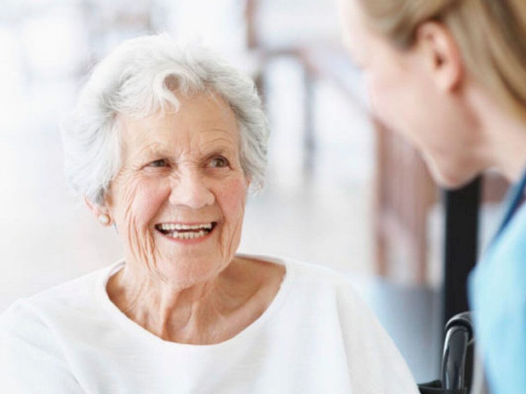 An elderly woman talking with a health care provider