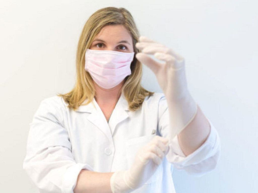 A female doctor is putting on her gloves to top the spread of infections COVID-19