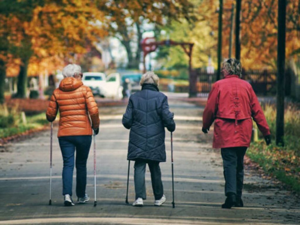 Three elderly women taking a efficient stroll in a city park in the winter to promote senior care