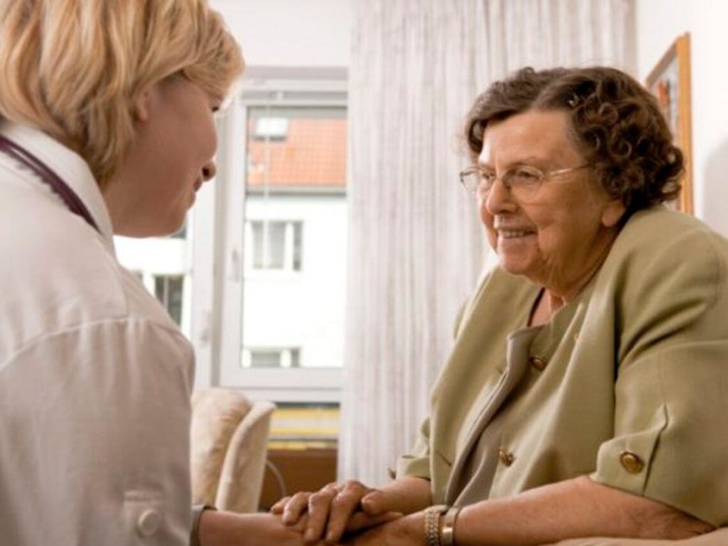 Healthcare worker giving comfort to patient sitting down in senior care facility
