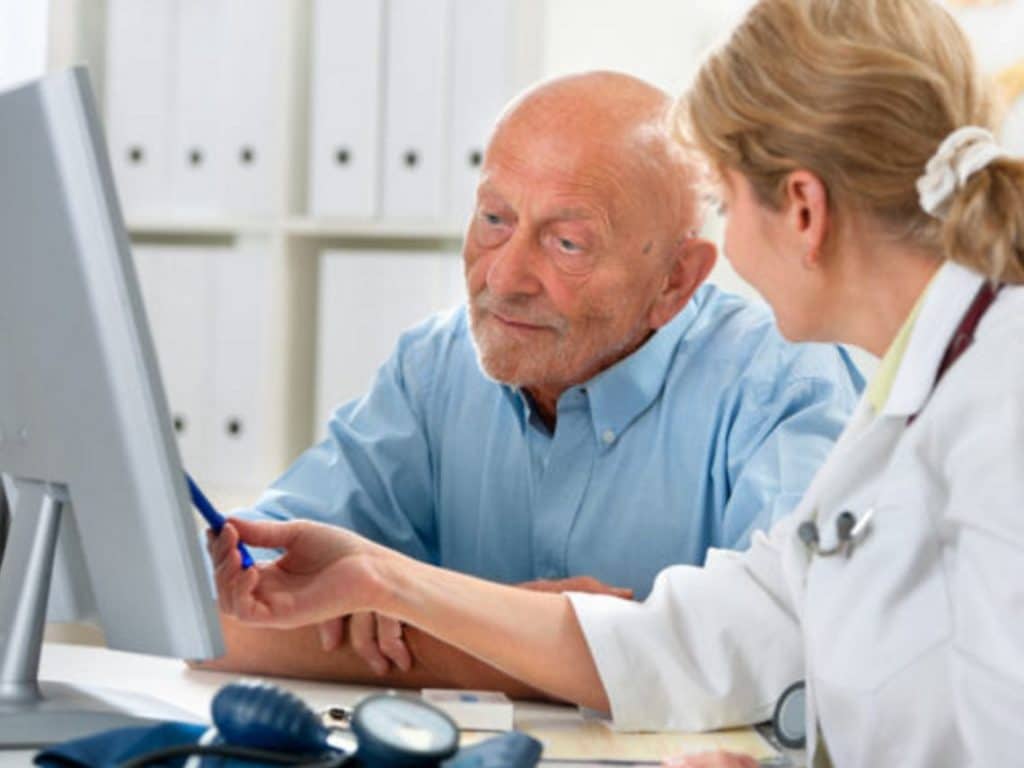 physician looking at computer with elderly man, telehealth services