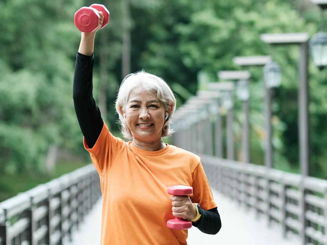 Senior woman smiling while doing hand weight exercises