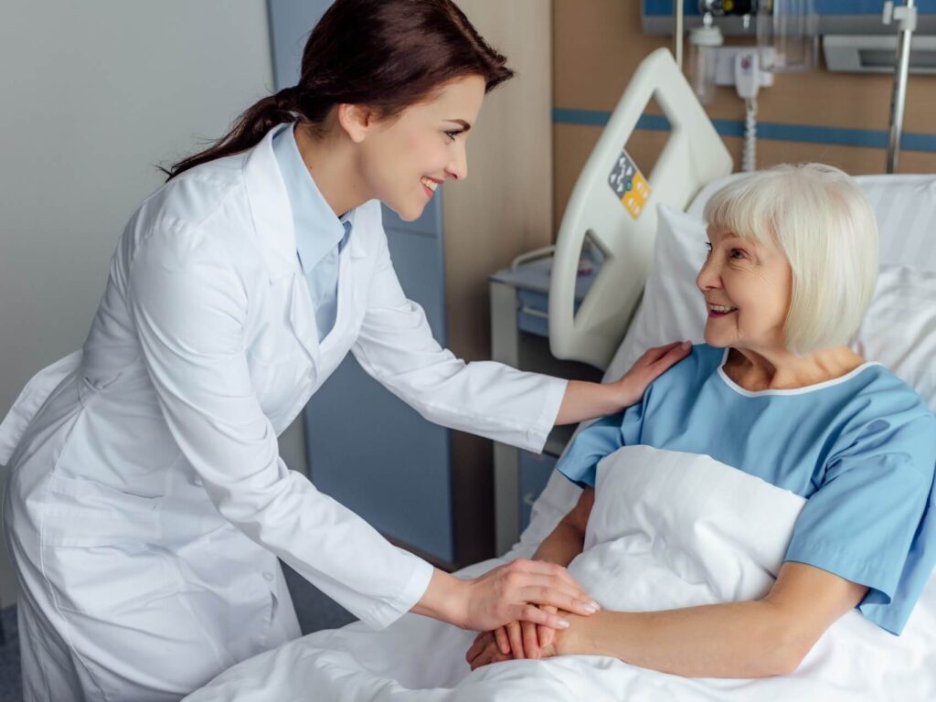 Smiling female doctor holding hand of older female patient